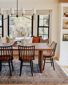 a dining room table with four chairs in front of it and a couch behind it