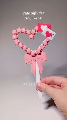 someone is holding up a heart shaped origami decoration with pink and white stars