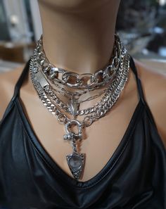This handmade chunky stainless steel chain layered necklace set is a stunning piece of jewelry that is perfect for those who love bold and edgy accessories. This is two necklaces, the big chunky choker that is adjustable with a built-in extender, and the 4-strand drop festoon design necklace (also adjustable). Adding depth and dimension to the piece is a u lock and arrowhead pendant. Very punk, grunge aesthetic! All the chains are made of sturdy stainless steel, ensuring durability and longevity, and making it completely hypoallergenic, waterproof, and non tarnish. It will look exactly like this forever!  This necklace set is an excellent handmade gift for someone special. It is a perfect choice for those who love alternative and goth styles, as well as anyone who wants to make a statement Heavy Chain Jewelry, Layered Silver Necklaces Grunge, Layered Goth Necklace, Gothic Chain Necklace, Punk Jewelry Necklaces, Goth Layered Necklaces, Layered Chunky Necklaces, Chunky Jewelry Aesthetic, Chunky Jewelry Necklace