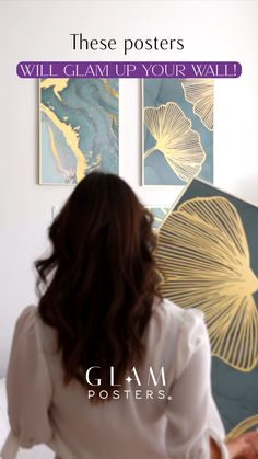 a woman is standing in front of some art on the wall with her back to the camera
