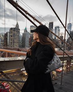 a woman standing on top of a bridge looking at the city skyline in the distance