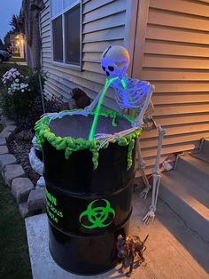 a skeleton sitting on top of a barrel in front of a house