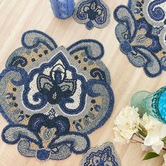 blue and gold placemats on a wooden table with white flowers in the foreground