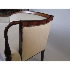 an antique chair with white upholstered fabric and wood trimming on the back