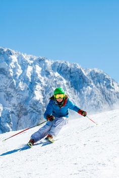 a person riding skis down a snow covered slope in front of a snowy mountain