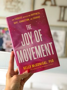 a person holding up a pink book in their hand with the title, the joy of movement