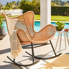 a wicker rocking chair next to a pool
