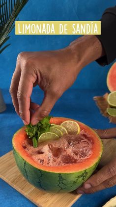 someone is cutting into a watermelon with limes and garnishes