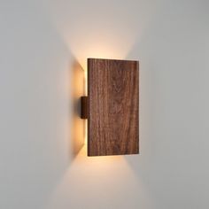 a wooden wall light mounted on the side of a white wall in a room with grey walls