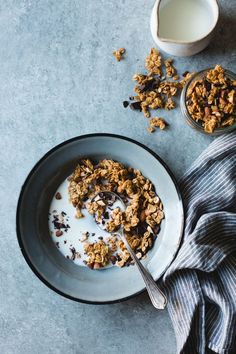 a bowl of granola next to a cup of milk