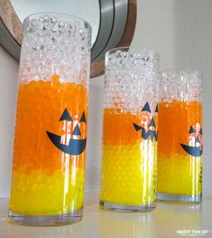 three glasses filled with orange liquid sitting on top of a white counter next to a mirror