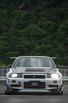 the front end of a white car driving on a race track