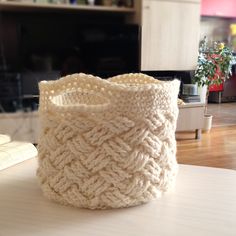 a white knitted basket sitting on top of a table in front of a tv