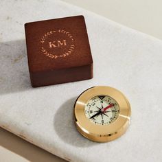 a gold clock sitting on top of a marble counter next to a wooden box with the word wm written on it