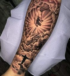 a man's arm with a cross and jesus on it, in the clouds