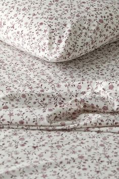 a close up view of a bed with floral sheets and pillow cases on top of each other