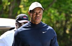 a man with a hat on walking next to another man wearing a white baseball cap