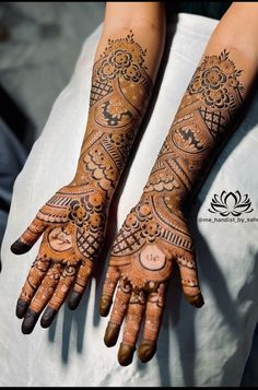 two hands with henna tattoos on them, one is showing off the intricate design