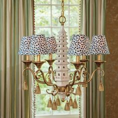 a white chandelier with leopard print lampshades in front of a window
