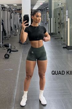 a woman taking a selfie in the gym with her cell phone and wearing shorts