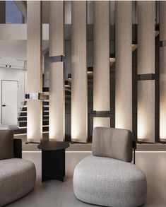 a living room filled with furniture next to a stair case covered in wooden slats