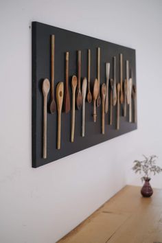 wooden spoons are mounted on the wall in front of a vase with a plant
