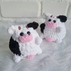 two small stuffed animals sitting on top of a white blanket