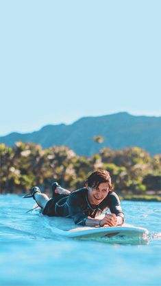 a man laying on a surfboard in the water with a bird sitting on his back