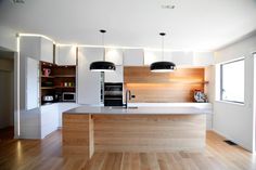 a kitchen with two stools and an island in front of the counter top is illuminated by black pendant lights