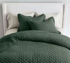 a bed with green comforters and pillows on it