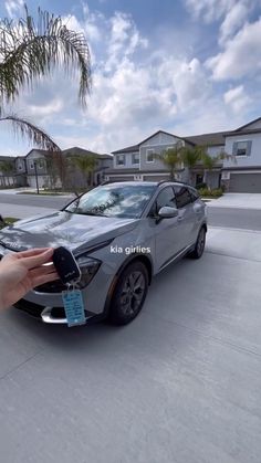 a person holding a car key in front of a silver vehicle with a blue tag on it