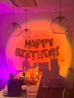 a birthday party with balloons and bottles on the bar counter in front of an orange and purple background
