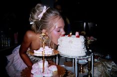 a woman blowing out the candles on a cake that is sitting on top of a table