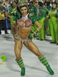 a woman in green and pink costume standing on top of a white floor next to other people