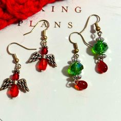 three pairs of earrings with red, green and silver beads on them sitting on top of a white surface