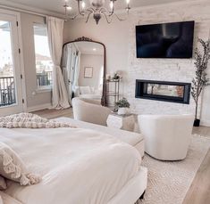 a bedroom with a large bed, white furniture and a flat screen tv mounted on the wall