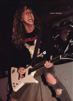 a man with long hair playing an electric guitar