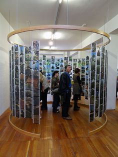 a group of people standing around in a room with pictures on the walls and wood floors