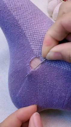 someone is cutting through the side of a purple sock