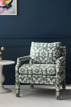 a chair sitting next to a table in front of a wall with blue paint on it