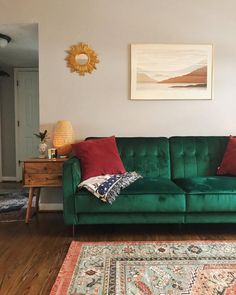 a green couch sitting in the middle of a living room next to a wooden table