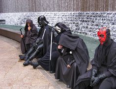 some people in costume sitting on the ground with their faces painted like darth vader