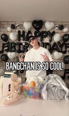 a man standing in front of a table with stuffed animals and balloons on the wall