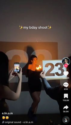 two women holding up cell phones with candles in front of them and the number twenty behind them