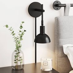 a black lamp next to a vase with a plant in it