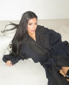 a woman laying on top of a white couch next to a black jacket and high heels