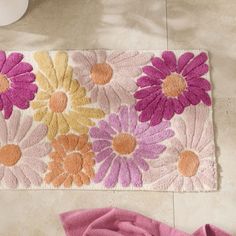 a pink rug with flowers on it next to a white vase and flower potted plant