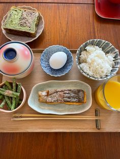 an assortment of food is displayed on a wooden table with chopsticks and bowls