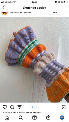 an orange and purple knitted object hanging on a wall