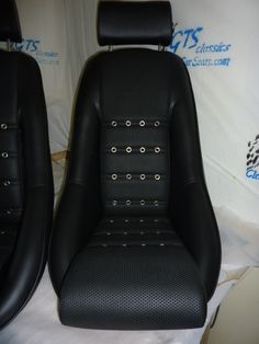 two black leather seats sitting next to each other on a white cloth covered tablecloth